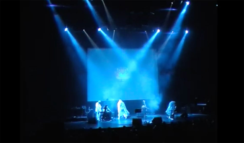 The band Coil live on stage at the Barbican. Four figures on stage saturated by blue light.