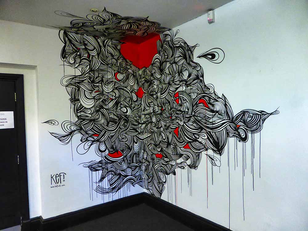 Abstract artwork by KEF! painted directly on the walls in the foyer of Genesis Cinema. It's a line drawing in black with red features