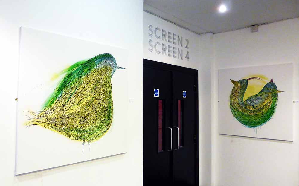 two paintings by KEF! of birds in yellow and green on either side of doors to cinema screens